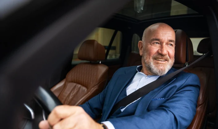 Ondernemer achter het stuur van zijn auto, onderweg naar een afspraak