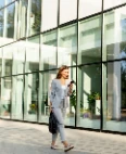 Young professional walking past an office building with her phone