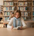 Student reading in a bright library